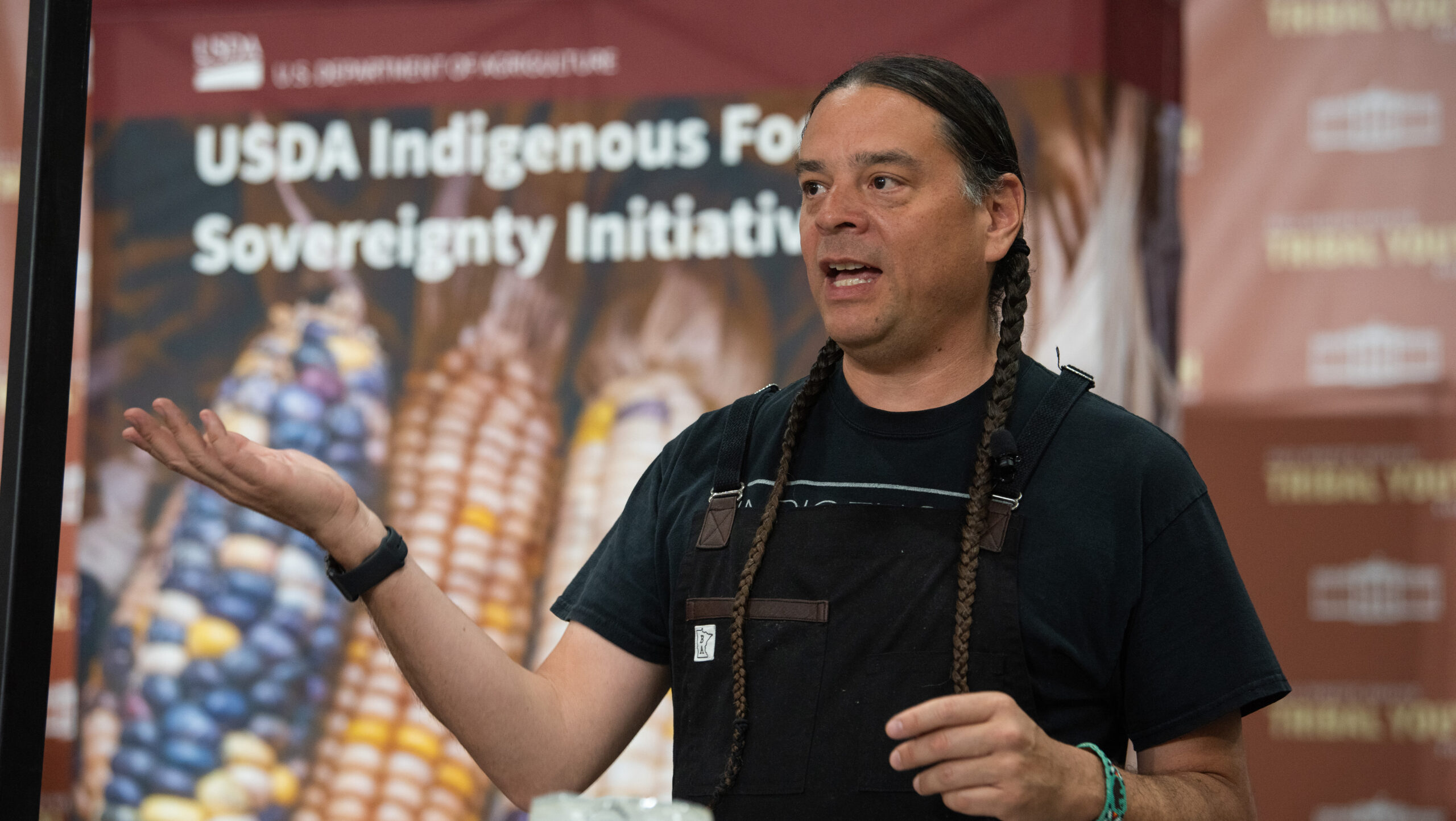 Chef Sean Sherman speaks in front of a sign that says “USDA Indigenous Food Sovereignty Initiative”